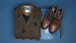 Box mit braunem Mantel, blauer Jeans und braunen Lederschuhen